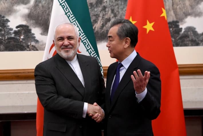 El ministro de Asuntos Exteriores de China, Wang Yi, estrecha la mano del ministro de Asuntos Exteriores de Irán, Mohammad Javad Zarif, durante una reunión en la residencia de huéspedes estatal Diaoyutai, en Beijing, el 31 de diciembre de 2019. (Noel Celis - Pool/Getty Images)