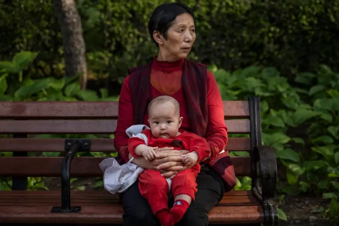 Una mujer sostiene a un bebé en un parque de Beijing, China, el 12 de mayo de 2021. (Kevin Frayer/Getty Images).