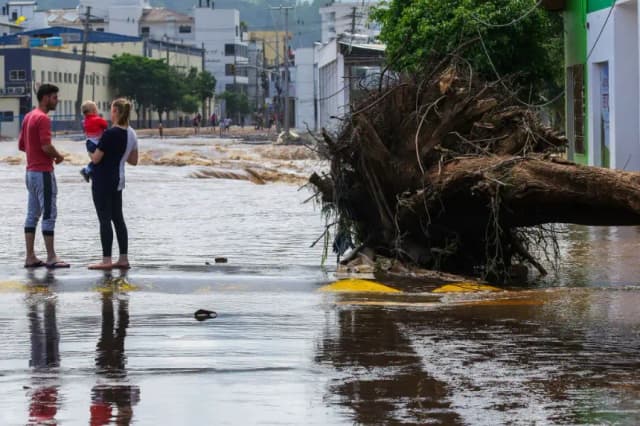 Los lugareños permanecen junto a un árbol caído luego de las inundaciones causadas por las fuertes lluvias, en Roca Sales, estado de Rio Grande do Sul, Brasil, el 19 de noviembre de 2023. (Silvio Avila/AFP vía Getty Images)