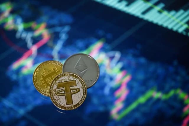 Una ilustración muestra monedas de criptomonedas Tether (USDT), Bitcoin y Ethereum chapadas en oro dispuestas junto a una pantalla que muestra un gráfico de cotización, en Londres, el 8 de mayo de 2022. (Justin Tallis/AFP a través de Getty Images)

