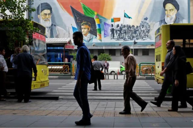 Los peatones caminan frente a un mural que muestra al difunto fundador revolucionario iraní, el ayatolá Jomeiní (d), al líder iraní, el ayatolá Alí Jamenei (i), y a la fuerza paramilitar Basij, en el centro de Teherán, Irán, el 12 de mayo de 2016. Vahid Salemi/Foto AP
