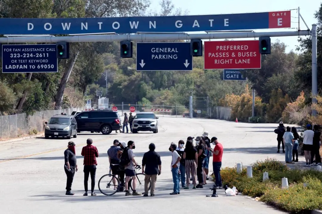 La gente observa cómo los agentes federales se despliegan frente a la puerta E del Dodger Stadium de Los Ángeles el 19 de junio de 2025. (Myung J. Chun/Los Angeles Times vía AP).