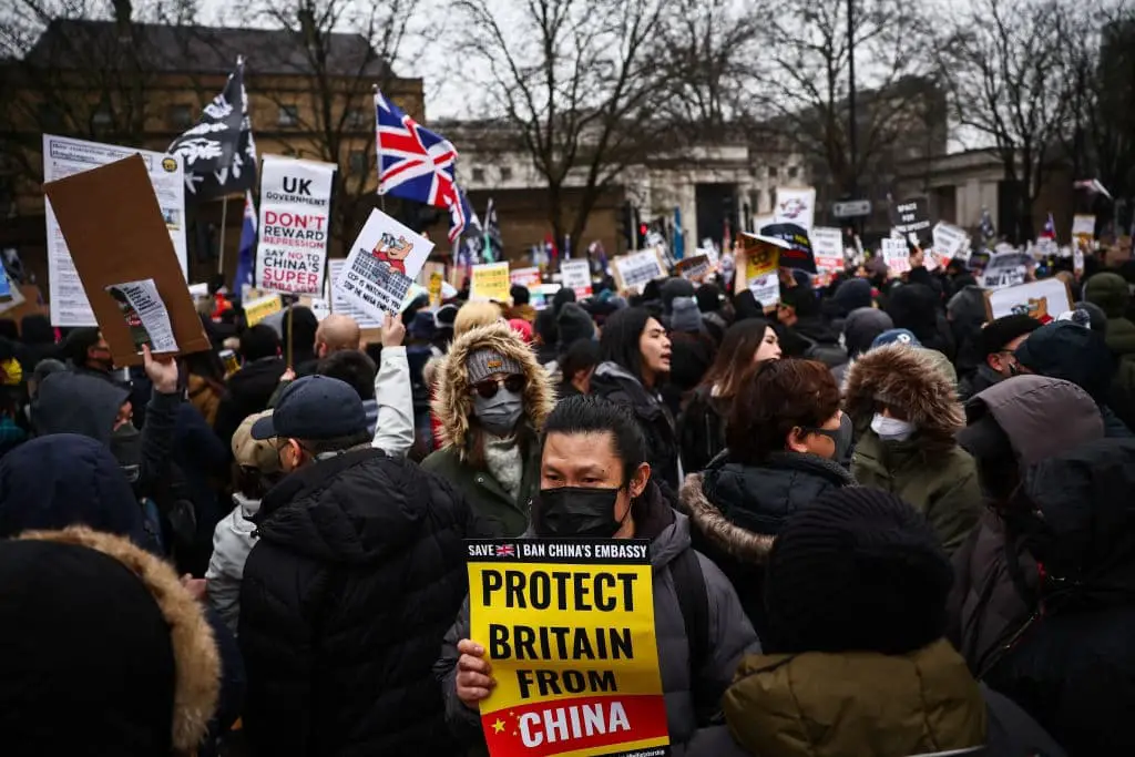 Manifestantes portan pancartas en el antiguo emplazamiento de la Real Casa de la Moneda de Londres el 8 de febrero de 2025 para protestar contra la propuesta de trasladar la embajada de China a este lugar, cercano a la Torre de Londres. (Henry Nicholls/AFP).