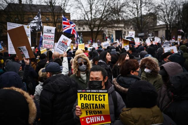 Manifestantes portan pancartas en el antiguo emplazamiento de la Real Casa de la Moneda de Londres el 8 de febrero de 2025 para protestar contra la propuesta de trasladar la embajada de China a este lugar, cercano a la Torre de Londres. (Henry Nicholls/AFP).