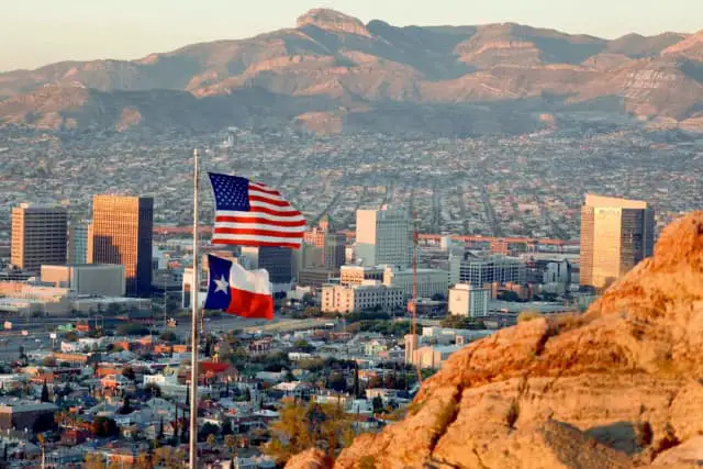 Una bandera estadounidense y otra tejana ondean frente al horizonte de El Paso y Ciudad Juárez, en El Paso, Texas, el 23 de septiembre de 2022. (Joe Raedle/Getty Images)
