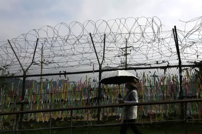 Una mujer camina junto a cintas de oración deseando la reunificación de las dos Coreas en la cerca de alambre en el Pabellón Imjingak, cerca de la zona desmilitarizada (DMZ) el 19 de julio de 2023 en Paju, Corea del Sur. (Chung Sung-Jun/Getty Images)