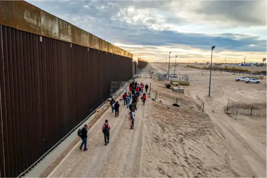 Inmigrantes ilegales caminan junto al muro fronterizo entre Estados Unidos y México tras cruzar el Río Grande hacia El Paso, Texas, el 1 de febrero de 2024. (John Moore/Getty Images)