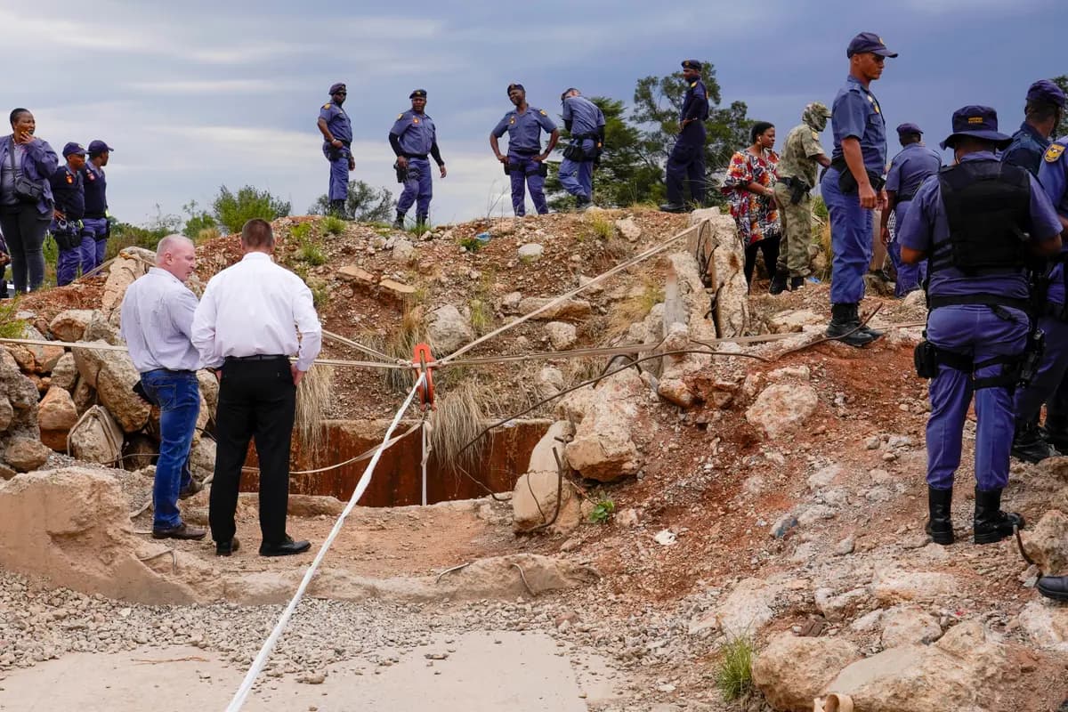 <em>Agentes de policía y personal de seguridad privada se encuentran en la entrada de una mina de oro reformada donde hay mineros ilegales atrapados en Stilfontein, Sudáfrica, el 15 de noviembre de 2024. Denis Farrell/AP Photo</em>