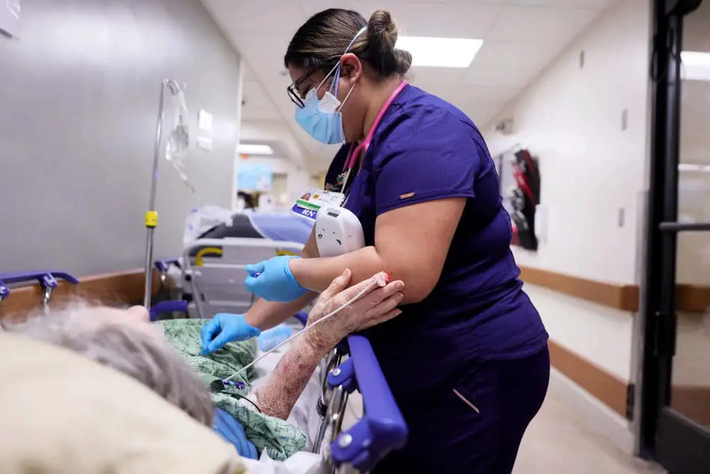 Una enfermera titulada atiende a un paciente en una camilla en el pasillo de la saturada sala de urgencias del Providence St. Mary Medical Center, en medio de la pandemia COVID-19, en Apple Valley, California, el 5 de enero de 2021. (Mario Tama/Getty Images).
