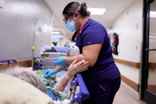 Una enfermera titulada atiende a un paciente en una camilla en el pasillo de la saturada sala de urgencias del Providence St. Mary Medical Center, en medio de la pandemia COVID-19, en Apple Valley, California, el 5 de enero de 2021. (Mario Tama/Getty Images).