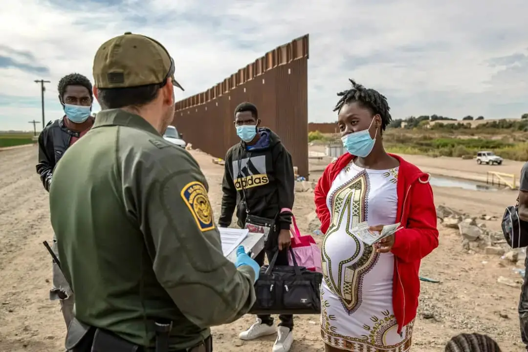 Inmigrantes ilegales, entre ellos una mujer haitiana embarazada que intentaba dar a luz en Estados Unidos, son detenidos por un agente de la Patrulla Fronteriza de Estados Unidos en Yuma, Arizona, el 7 de diciembre de 2021. (John Moore/Getty Images)
