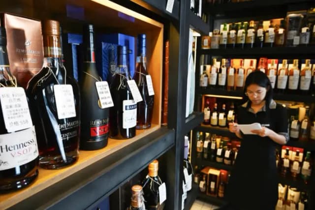 Una vendedora cerca de un estante con botellas de coñac en una licorería de Beijing, el 4 de julio de 2025. (Greg Baker/AFP vía Getty Images)