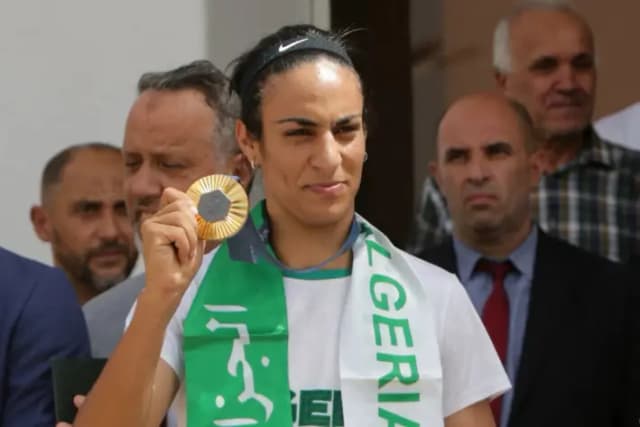 La boxeadora argelina Imane Khelif, quien ganó la medalla de oro en boxeo de peso welter femenino en los Juegos Olímpicos, sostiene la medalla a su llegada al aeropuerto de Argel, Argelia, el 12 de agosto de 2024. (Ramzi Boudina/Reuters)