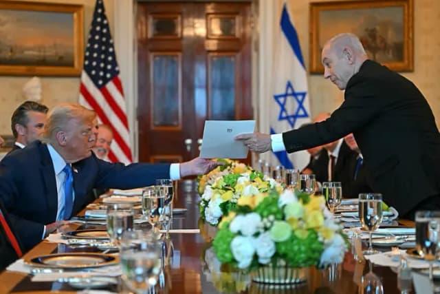 El primer ministro israelí, Benjamin Netanyahu (der.), entrega una carta al presidente estadounidense, Donald Trump, durante su reunión en el Salón Azul de la Casa Blanca, en Washington, D.C., el 7 de julio de 2025. (ANDREW CABALLERO-REYNOLDS/AFP vía Getty Images)