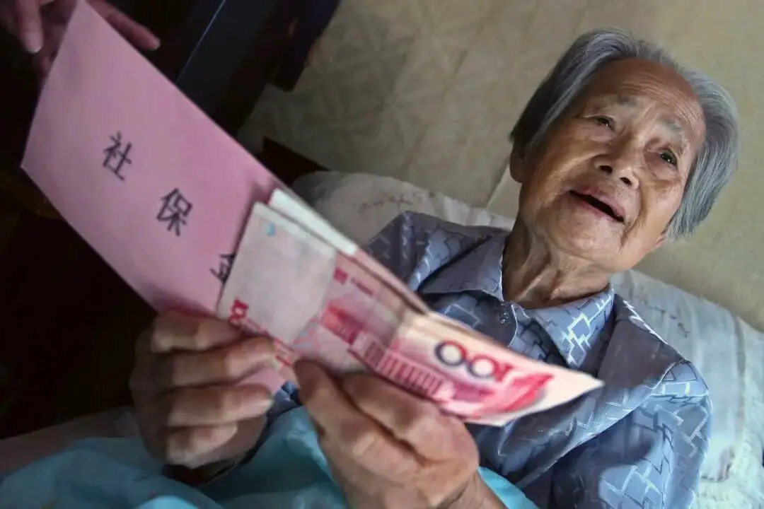 Hu Axiang, de 88 años, recibe su primera pensión en su casa de Shanghái (China) el 28 de septiembre de 2006. (China Photos/Getty Images)