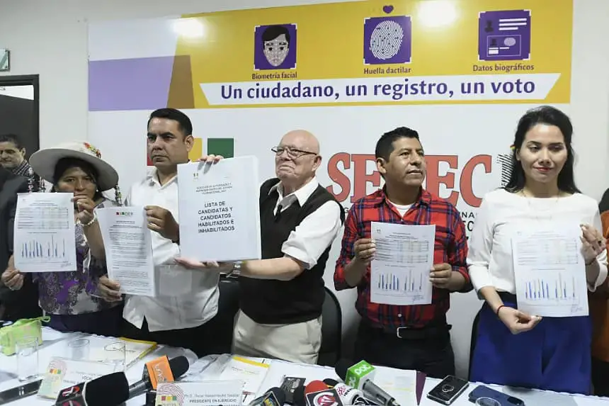 El presidente del Tribunal Supremo Electoral (TSE) de Bolivia, Oscar Hassenteufel (c), muestra la lista publicada de candidatos habilitados y no habilitados para las elecciones generales de Bolivia, junto al vocal Francisco Vargas (c-i) y Tahuichi Tahuichi Quispe (c-d), durante una conferencia de prensa en Santa Cruz, Bolivia, el 6 de junio de 2025. (Rodrigo Urzagasty/AFP vía Getty Images)