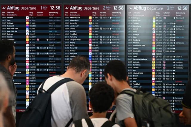 Los pasajeros se encuentran frente a una pantalla que anuncia vuelos en el Aeropuerto BER de Berlín-Brandeburgo en Schoenefeld, al suroeste de la capital alemana, el 19 de julio de 2024. (Ralf Hirschberger/AFP vía Getty Images)