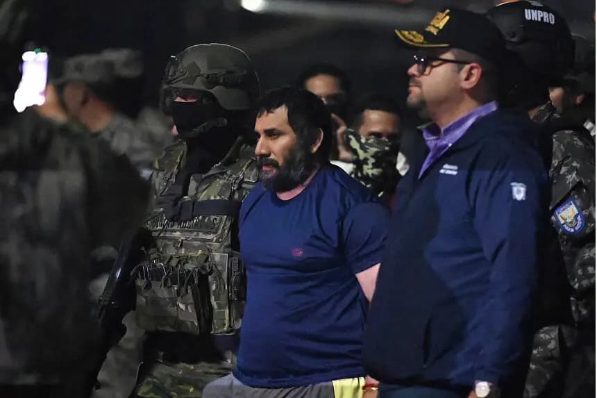 El narcotraficante Adolfo Macias, alias Fito, es custodiado por el ministro del Interior de Ecuador, John Reimberg (derecha), y personal militar a su llegada a la base aérea de Guayaquil, Ecuador, el 25 de junio de 2025, tras su recaptura en Manta, provincia de Manabí. (MARCOS PIN/AFP a través de Getty Images)