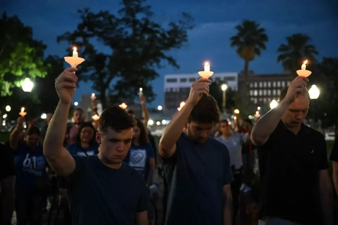 La gente sostiene velas mientras participa en una vigilia por las víctimas de las inundaciones durante el fin de semana del 4 de julio, en Travis Park, San Antonio, Texas, el 7 de julio de 2025. (Ronaldo Schemidt/AFP vía Getty Images)