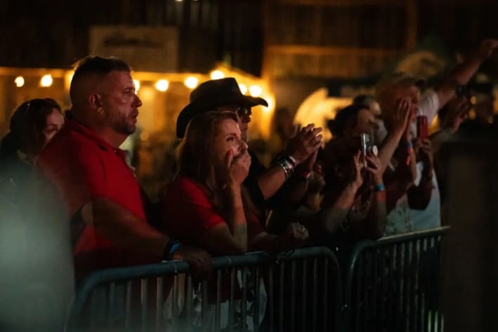 Helen Comperatore mira a sus hijas Kaylee y Allyson mientras hablan durante una canción de Gary Buck III en honor a Corey Comperatore en Russellton, Pensilvania, el 12 de julio de 2025. (Samira Bouaou/The Epoch Times)