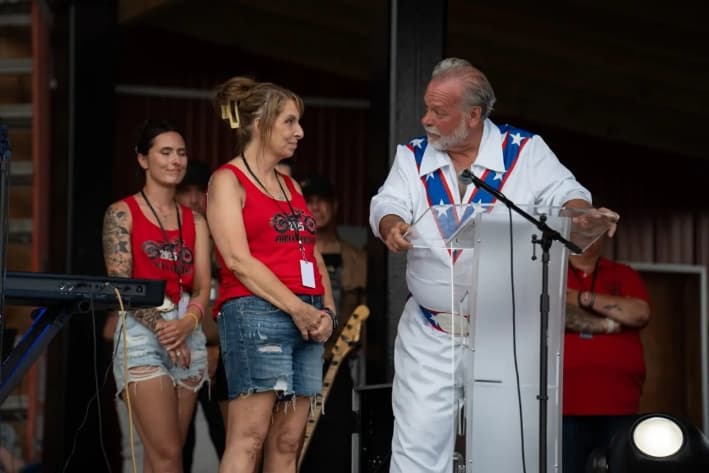El organizador Scott Docherty y Helen Comperatore hablan en un concierto de Gary Buck III en honor a Corey Comperatore, en Russellton, Pensilvania, el 12 de julio de 2025. (Samira Bouaou/The Epoch Times)