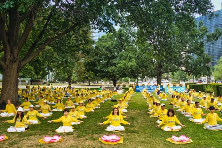 Practicantes de Falun Gong demuestran los ejercicios de meditación de la práctica durante un evento celebrado en el Queen's Park de Toronto, el 13 de julio de 2025 para conmemorar el 26.° aniversario de la persecución del Partido Comunista Chino contra Falun Gong. (Jerry Zhang/The Epoch Times)