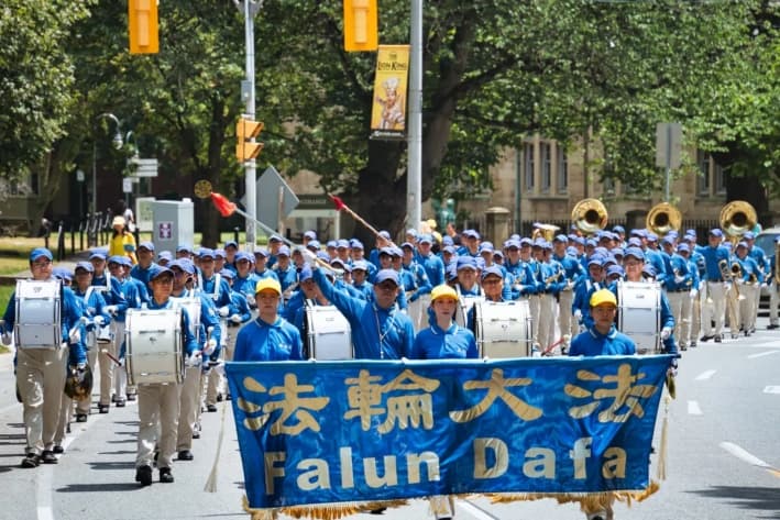 La banda de música Tian Guo participa en un desfile por el centro de Toronto para conmemorar el 26.° aniversario de la persecución contra Falun Gong en China, el 13 de julio de 2025. (Jerry Zhang/The Epoch Times)