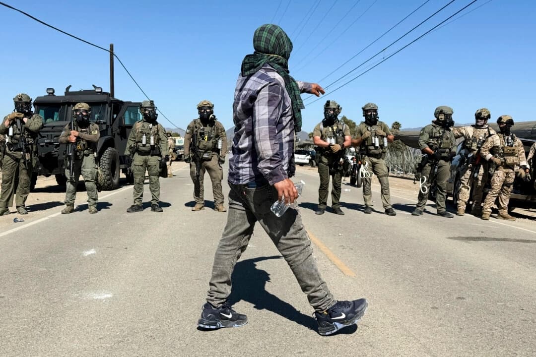 Un manifestante camina frente a agentes federales que bloquean una carretera durante una operación de inmigración en Camarillo, California, el 10 de julio de 2025. (Michael Owen Baker/AP Photo)

