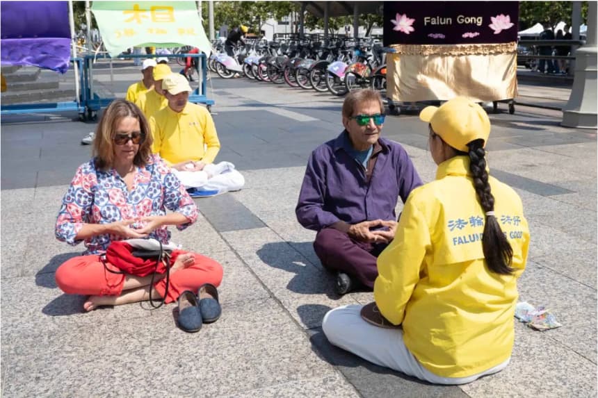 Sam (2o-d) aprende el quinto ejercicio de Falun Gong en Harry Bridges Plaza, en San Francisco, el 12 de julio de 2025. (Gary Wang/The Epoch Times)