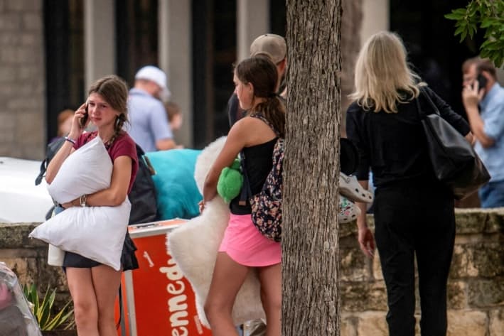 Una niña habla por teléfono en una zona donde las familias se reunían con los campistas tras las inundaciones mortales en Kerville, Texas, el 5 de julio de 2025. (Sergio Flores/Reuters)