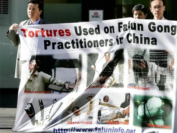 Practicantes de Falun Gong exhiben una pancarta que muestra recreaciones de torturas cerca del barrio chino de Sídney el 20 de julio de 2005. (Greg Wood/AFP/Getty Images)
