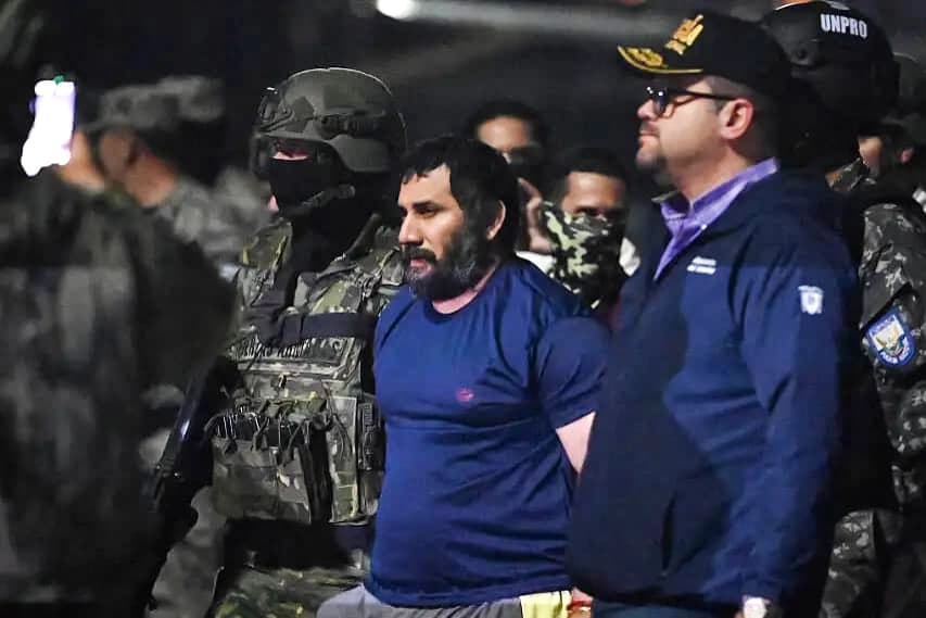 El narcotraficante Adolfo Macías, alias Fito, es custodiado por el ministro del Interior ecuatoriano, John Reimberg (derecha), y personal militar a su llegada a la base aérea de Guayaquil tras su recaptura en Manta, provincia de Manabí, en Ecuador, el 25 de junio de 2025. (MARCOS PIN/AFP vía Getty Images)