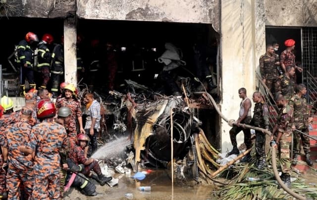 Bomberos y militares trabajan junto a los restos de un avión de entrenamiento de la fuerza aérea tras estrellarse en el campus de Milestone College, en Dhaka, Bangladesh, el 21 de julio de 2025. (Stringer/Reuters)