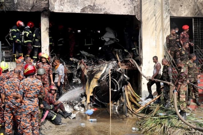 Bomberos y militares trabajan junto a los restos de un avión de entrenamiento de la fuerza aérea tras estrellarse en el campus de Milestone College, en Dhaka, Bangladesh, el 21 de julio de 2025. (Stringer/Reuters)