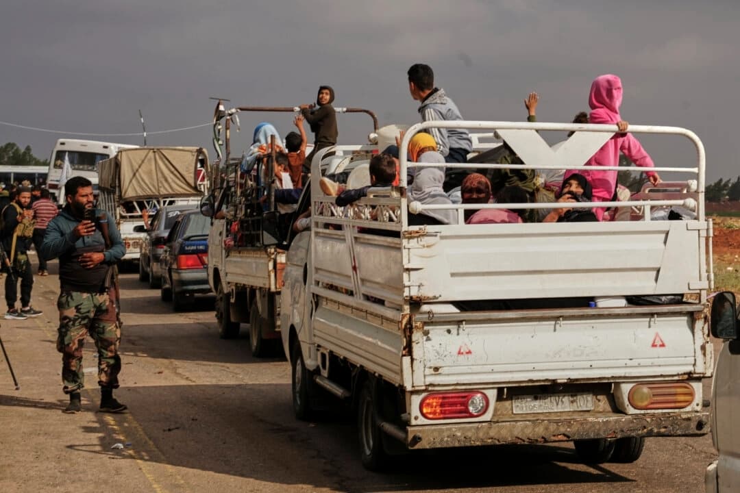 Familias beduinas sirias saludan mientras viajan en un convoy liderado por vehículos de la Media Luna Roja en Busra al-Harir, en dirección a Daraa tras ser evacuadas de Sweida, tras más de una semana de violentos enfrentamientos, el 21 de julio de 2025. (AP Photo/Malek Khattab)
