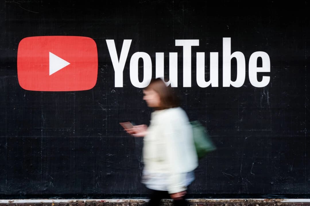 Una joven con un teléfono inteligente pasa junto a un anuncio publicitario de YouTube en Berlín, Alemania, el 27 de septiembre de 2019. (Sean Gallup/Getty Images)
