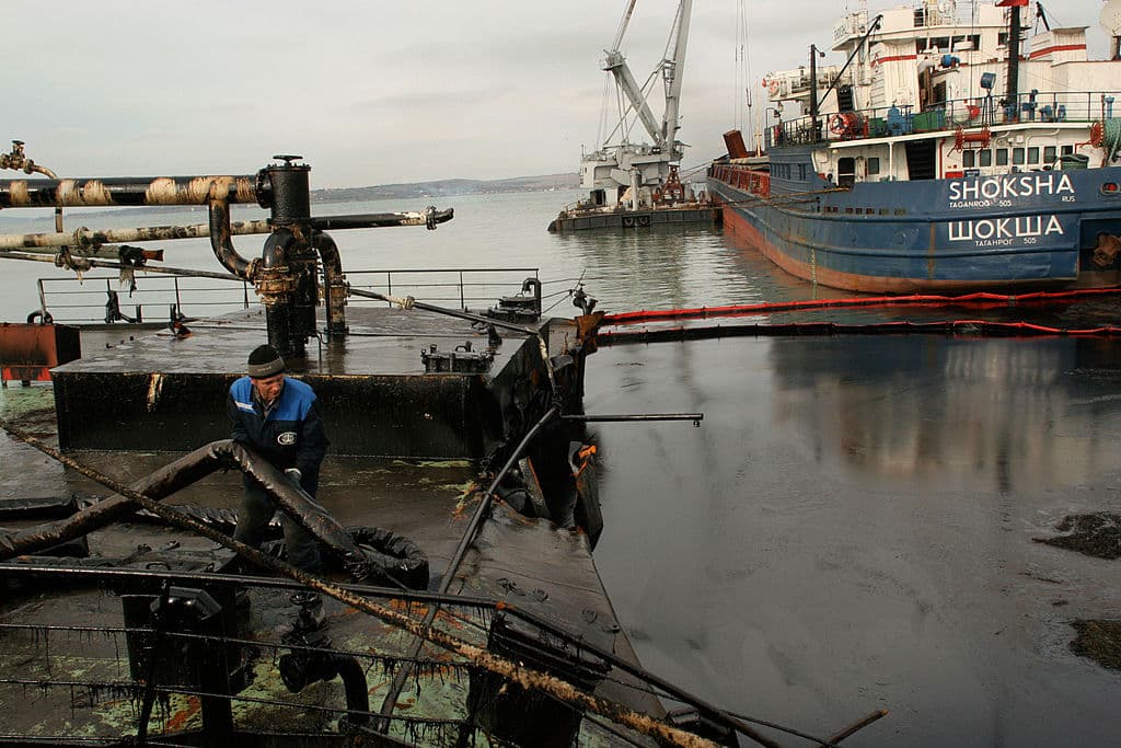 PORT KAVKAZ, RUSIA: Un trabajador intenta evitar que el petróleo se derrame por la popa del buque Voga-Neft, un petrolero que sufrió una grieta en el casco, el 17 de noviembre de 2007 en Port Kavkaz, en el estrecho de Kerch, en el mar Negro, en la región de Krasnodar, Rusia. Una fuerte tormenta hundió tres barcos rusos que transportaban azufre, agrietó el casco de un petrolero ruso y partió en dos otro petrolero ruso frente al puerto ucraniano de Kerch el 11 de noviembre, derramando hasta 2000 toneladas de fuelóleo en lo que un funcionario ruso calificó de «desastre medioambiental».  (Foto de Oleg Klimov/Epsilon/Getty Images)