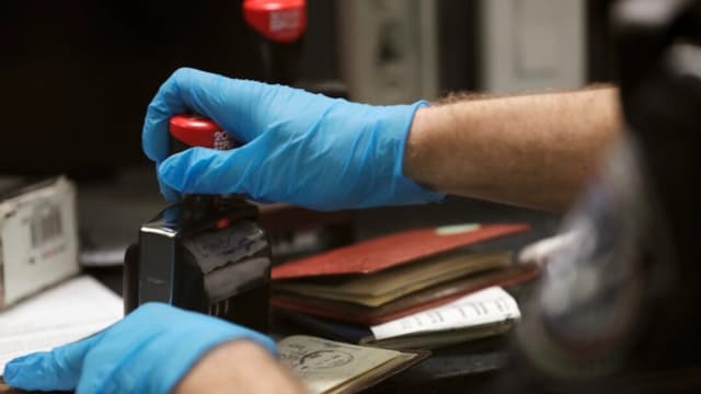 En esta fotografía de archivo, un agente de la Oficina de Operaciones de Campo de Aduanas y Protección Fronteriza sella un pasaporte tras autorizar la entrada de un viajero internacional en el Aeropuerto Internacional de Dulles, en Dulles (Virginia). (Glenn Fawcett/CBP)
