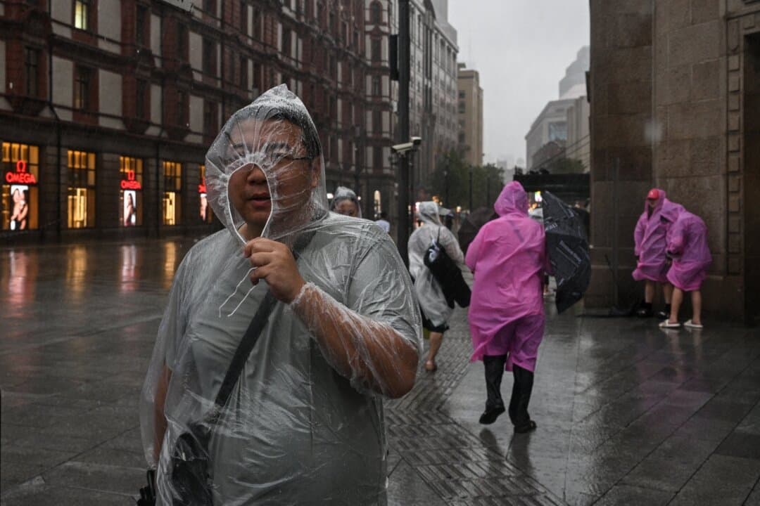 La gente se protege con ponchos desechables durante el paso del tifón Co-May en Shanghái el 30 de julio de 2025. (Héctor Retamal/AFP a través de Getty Images)