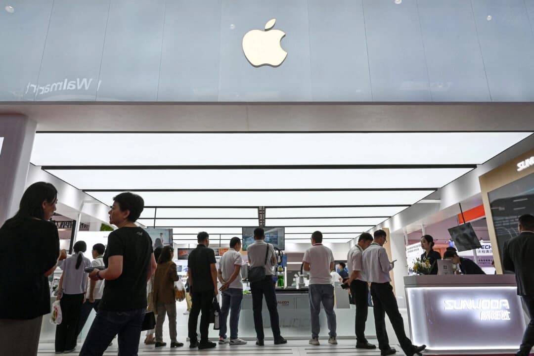 Los asistentes a la exposición pasan frente al stand de Apple y otros durante la Exposición Internacional de la Cadena de Suministro de China, celebrada en Beijing el 17 de julio de 2025. (Jade Gao/AFP a través de Getty Images).