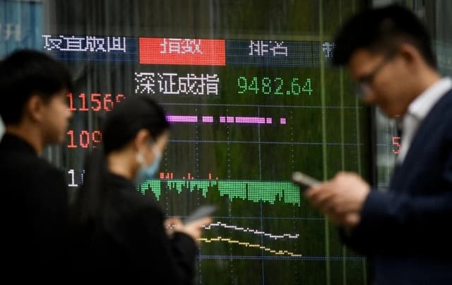 La gente pasa junto a una pantalla que muestra los movimientos del mercado bursátil chino, en Beijing, el 7 de abril de 2025. (Wang Zhao/AFP vía Getty Images)