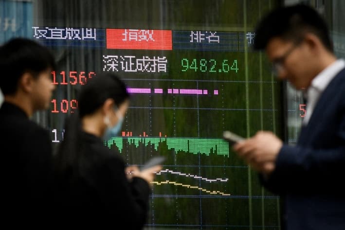 La gente pasa junto a una pantalla que muestra los movimientos del mercado bursátil chino, en Beijing, el 7 de abril de 2025. (Wang Zhao/AFP vía Getty Images)