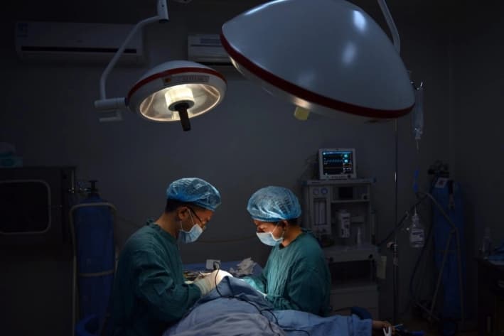 Un cirujano (izq.) realiza una operación a un paciente en la ciudad de Chongqing, en el suroeste de China, el 9 de agosto de 2013. (Peter Parks/AFP/Getty Images)