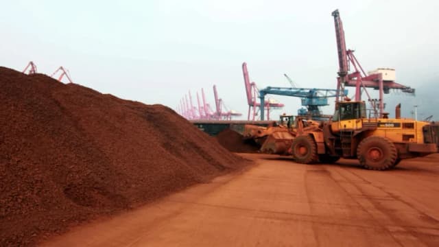 Un hombre que conduce un cargador frontal mueve tierra que contiene minerales de tierras raras para ser cargados en un puerto en Lianyungang, provincia de Jiangsu, China, el 5 de septiembre de 2010. (STR/AFP vía Getty Images)
