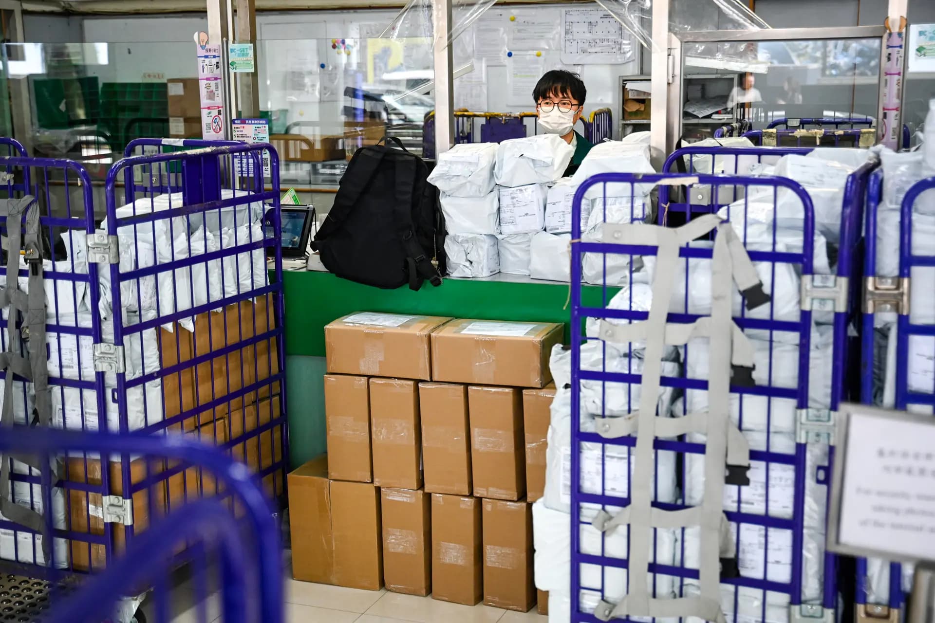 Paquetes apilados en el mostrador mientras un empleado de Hong Kong Post trabaja en una oficina de correos de Hong Kong el 16 de abril de 2025. La administración Trump anunció que todas las importaciones por valor de 800 dólares o menos estarán sujetas a aranceles y derechos, ampliando la suspensión de las exenciones para los envíos procedentes de China y Hong Kong promulgada en mayo. (Peter Parks/AFP a través de Getty Images)