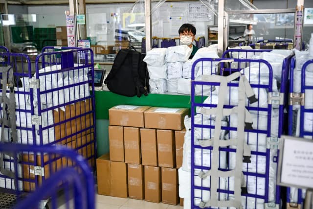 Paquetes apilados en el mostrador mientras un empleado de Hong Kong Post trabaja en una oficina de correos de Hong Kong el 16 de abril de 2025. La administración Trump anunció que todas las importaciones por valor de 800 dólares o menos estarán sujetas a aranceles y derechos, ampliando la suspensión de las exenciones para los envíos procedentes de China y Hong Kong promulgada en mayo. (Peter Parks/AFP a través de Getty Images)