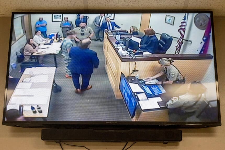 Andrew James McGann, acusado de dos cargos de asesinato con agravantes, aparece en el monitor de vídeo mientras comparece ante la juez de distrito Terra Stephenson para la vista de fianza en el centro de detención del condado de Washington. Viernes, 1 de agosto de 2025, en Fayetteville, Arkansas. Foto de AP/Michael Woods.
