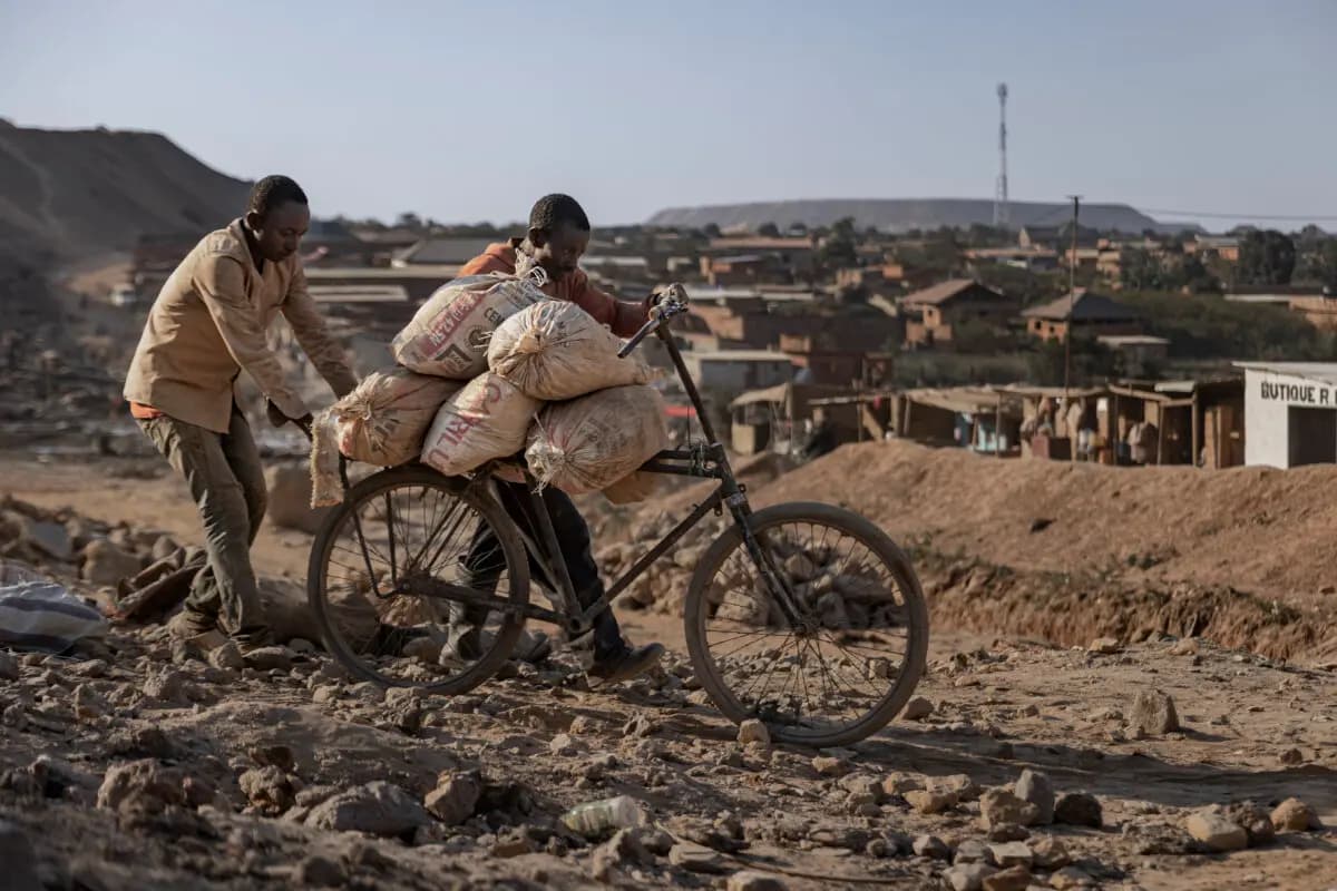 Un padre y su hijo empujan una bicicleta cargada con sacos de cobalto y cobre por un camino de tierra cerca de una mina artesanal en Kolwezi, República Democrática del Congo, el 25 de mayo de 2025. Michel Lunanga/Getty Images