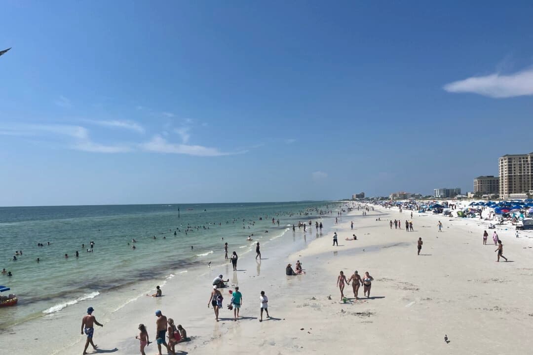 Turistas y lugareños juegan en las olas y la arena en Clearwater Beach, Florida, el 2 de julio de 2023. (Nanette Holt/The Epoch Times)
