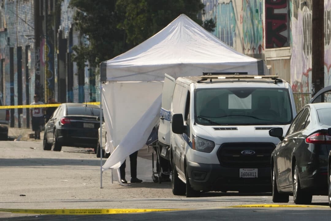 El forense del condado de Los Ángeles retira el cadáver de una víctima de un tiroteo cubierto con una lona blanca tras un tiroteo ocurrido durante la fiesta posterior a un festival de música en el centro de Los Ángeles el 4 de agosto de 2025. (Damian Dovarganes/AP Photo)
